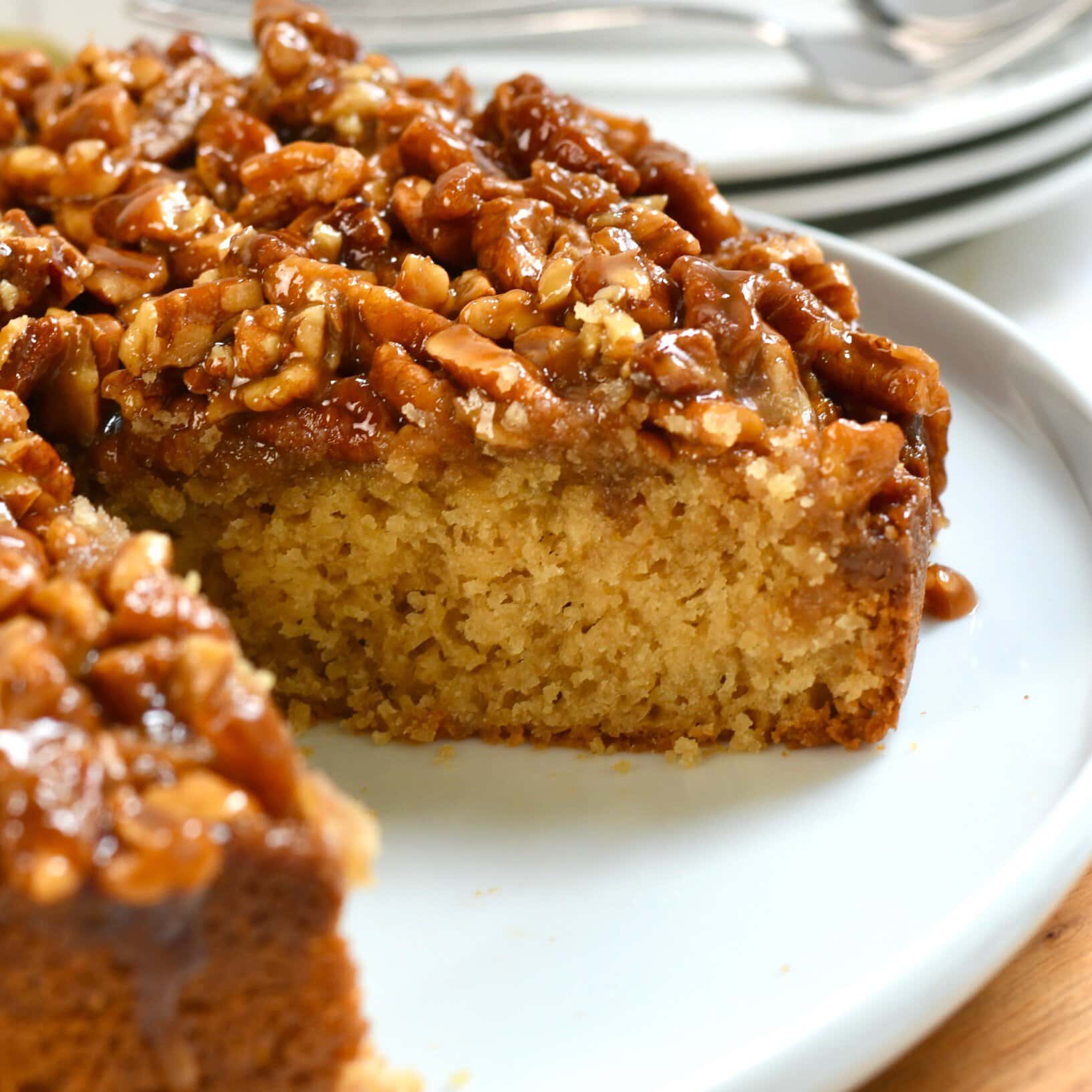 Side view of a pecan upside down cake with a slice missing to show the inside.