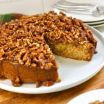 Pecan upside down cake served on a plate with a slice missing.