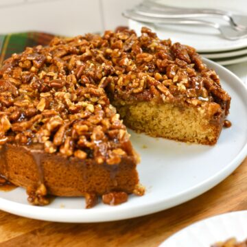 Pecan upside down cake served on a plate with a slice missing.