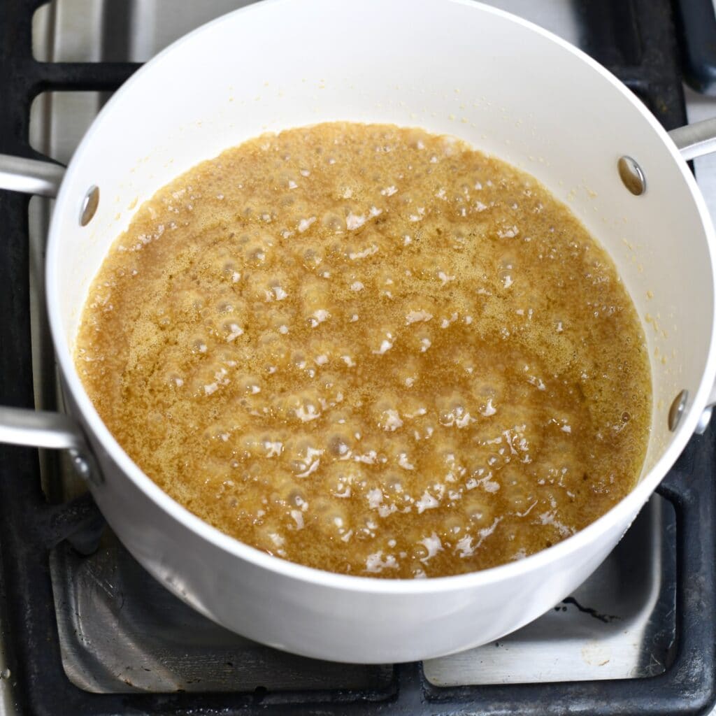 Simmering the caramel topping in a saucepan before adding the pecans.