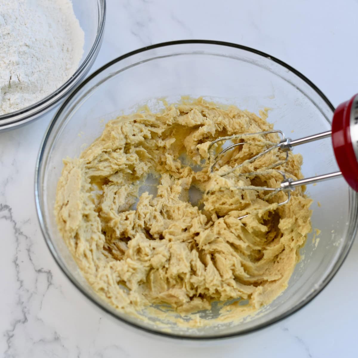 Using a hand mixer to mix together the rice krispie cookie dough.