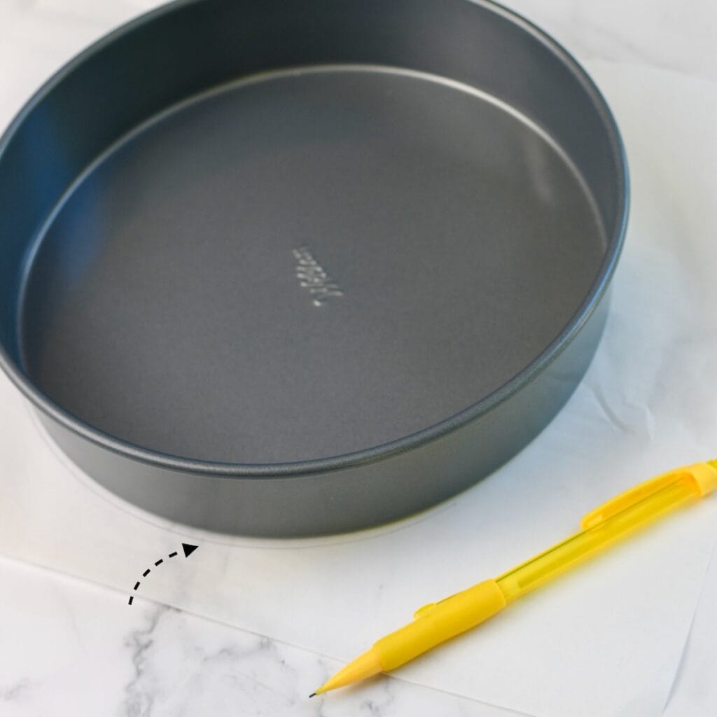 Round cake pan with pencil marking around the pan on parchment paper.