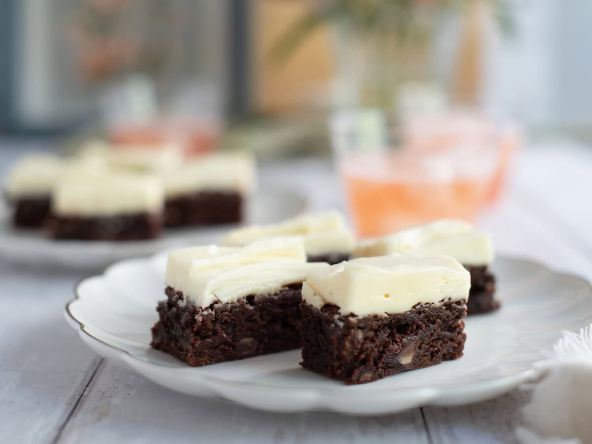Brownies with cream cheese frosting served on a plate.