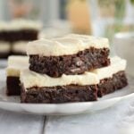 Side view of brownies with cream cheese frosting placed on a plate.