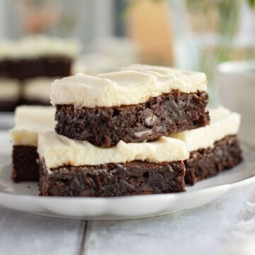 Side view of brownies with cream cheese frosting placed on a plate.