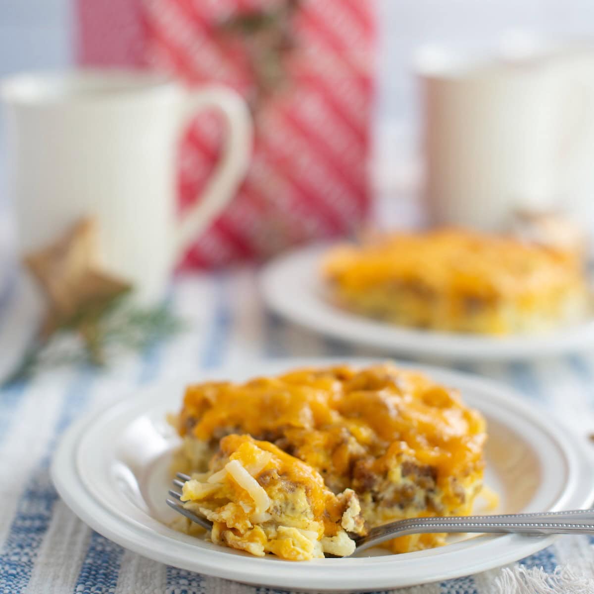 Fork taking a bite of a portion of sausage and hashbrown breakfast casserole on a plate.