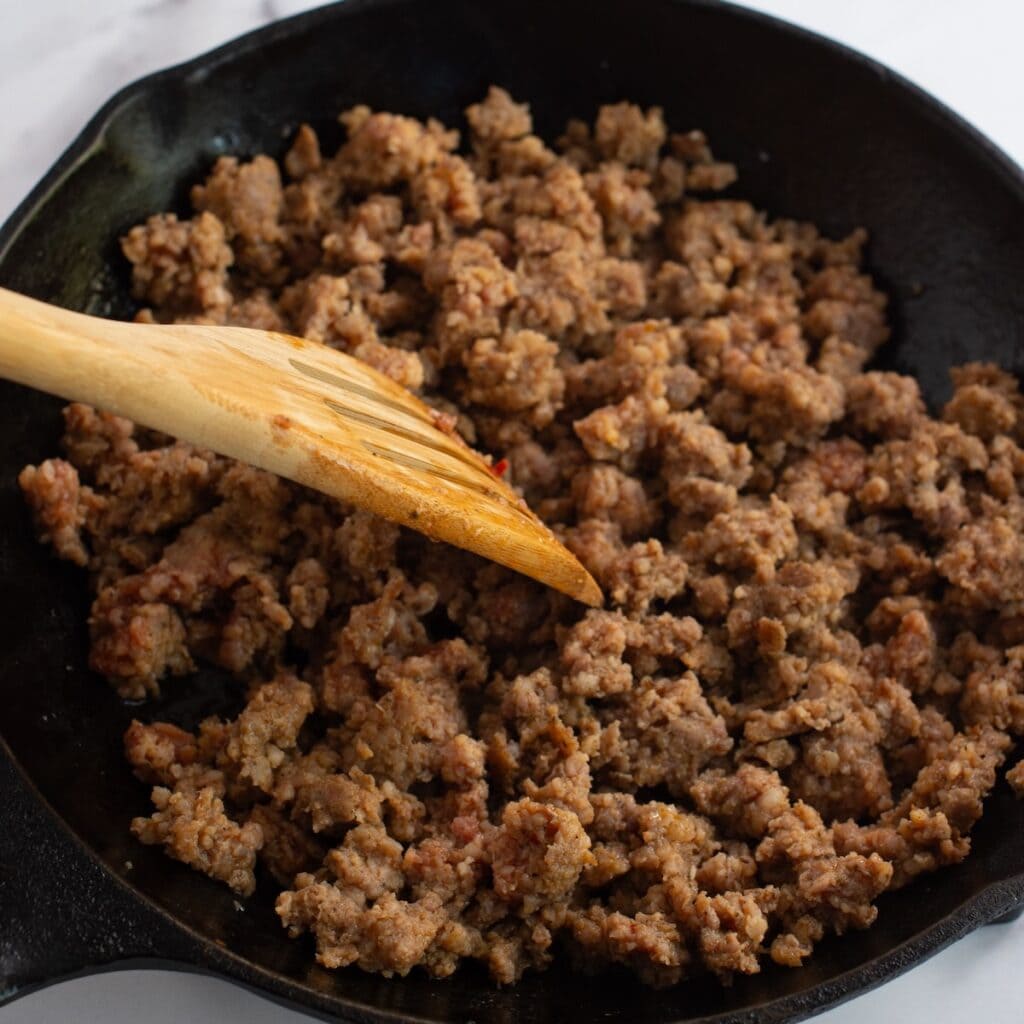 Ground sausage browning in a skillet.