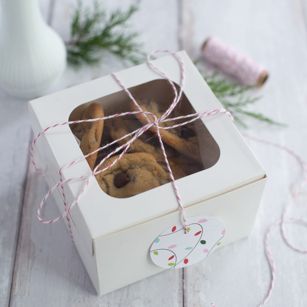 White gift box with chocolate chip cookies inside and a twine wrapped around it.